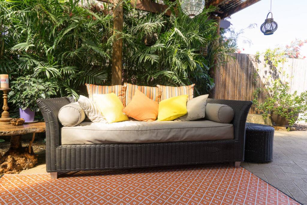 Sofa daybed with the orange pillows An outdoor seating area with water resistant covers on the cushions and several colorful pillows in orange and yellow tones on top