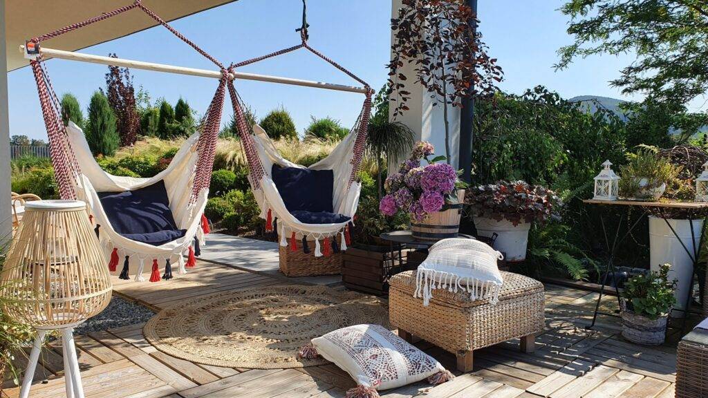 Ogrodowy taras, miejsce z huśtawką na letni wypoczynek w ogrod colorful relaxing nook in a mediterranean patio with cushion covers and hammocks