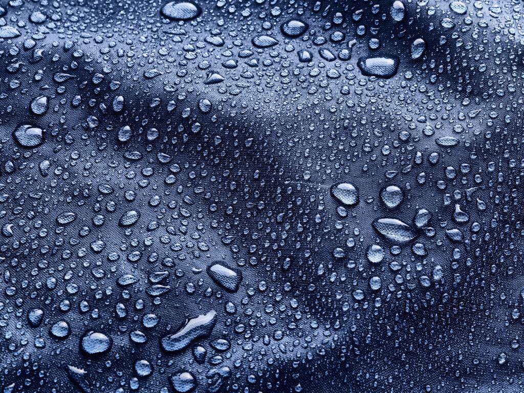 Rain water droplets on blue fiber waterproof fabric. Blue background. a Water-Resistant Mattress Cover